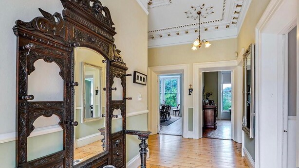 A hallway with a large ornate mirror, wooden flooring, and a ceiling with decorative moldings. - Fabulous 6 Bedroom Victorian Period House (Londonderry)