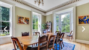 A dining room with a large wooden table, six chairs, and two paintings on the walls. - Fabulous 6 Bedroom Victorian Period House (Londonderry)