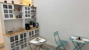 A compact kitchenette with a coffee maker, jars, and a bread box. There are two foldable chairs and a small table with a decorative plate. - Caltur B&B (Palermo)