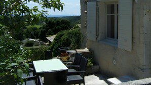 A patio with a table and chairs, a potted plant, and a view of a rural landscape.