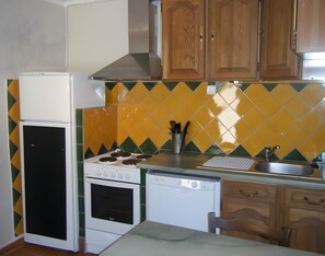 A compact kitchen with a refrigerator, stove, oven, dishwasher, and wooden cabinets.