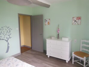 A child's room with a bed, dresser, chair, and a door leading to another room.