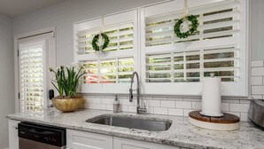 A kitchen with white cabinets, a granite countertop, a stainless steel sink, and a dishwashing unit.
