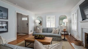 A living room with a grey sofa, a wooden coffee table with decorative balls, a fireplace, and a large mirror.