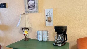 Ein grüner Holzschrank mit Kaffeemaschine und zwei Tassen darauf.