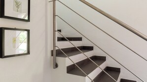 A staircase with a metal handrail and dark steps against a white wall. - Terrazza al Poggio by Wonderful Italy (Porto Rotondo)