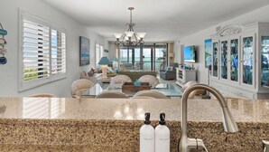 A spacious living area with a kitchen island, a chandelier, and a view of the ocean. - Beautiful panoramic views of the Gulf, 2 bedroom w/sleeping den, 2 bath condo (Sanibel)