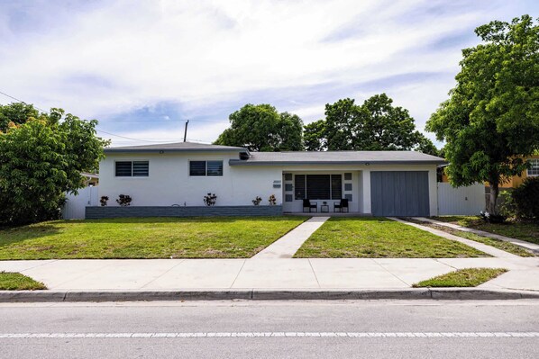 Une maison de plain-pied avec un garage, une pelouse devant et une allée.