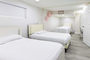 Une chambre avec deux lits, une porte blanche et un plancher de couleur claire.