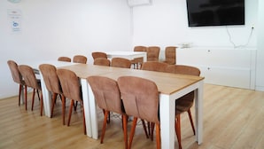 A conference room with a wooden table and matching chairs, a clock, and a flat-screen TV on the wall. - HOTEL GREEN GARDEN (Bucharest)