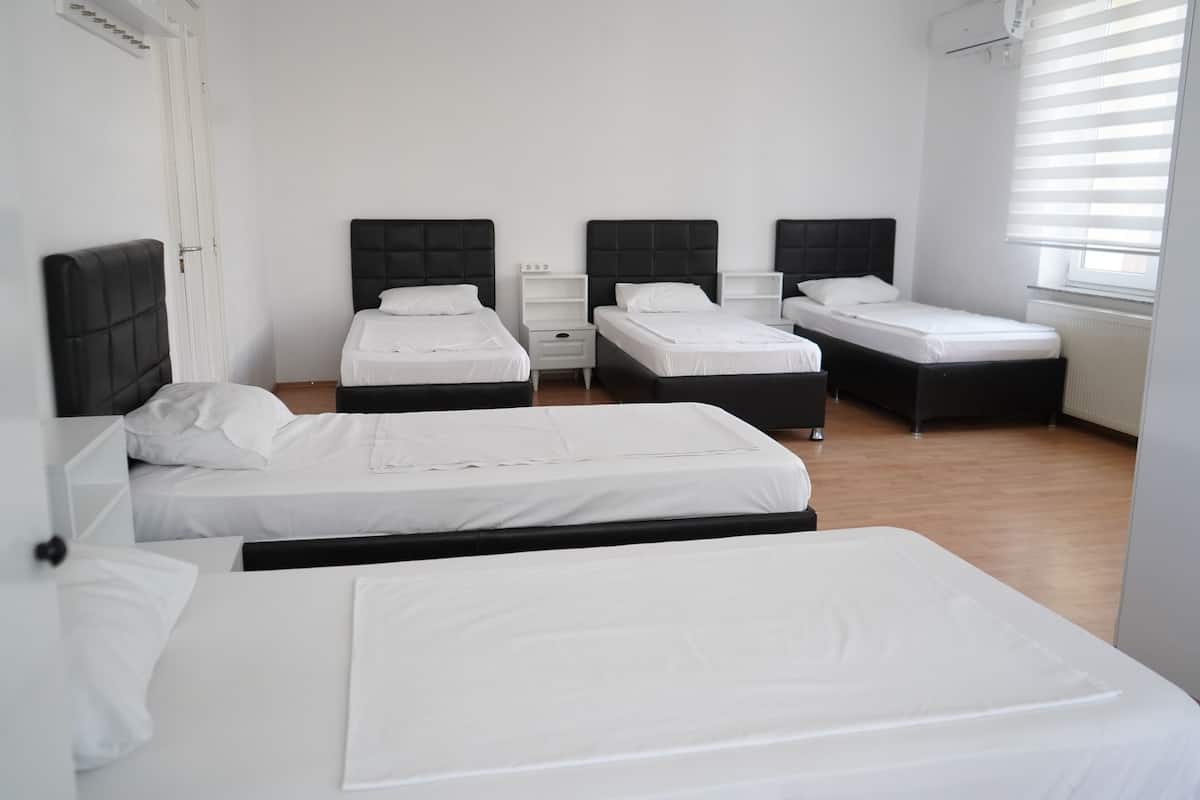 A hotel room with three beds, white bedding, and black headboards.