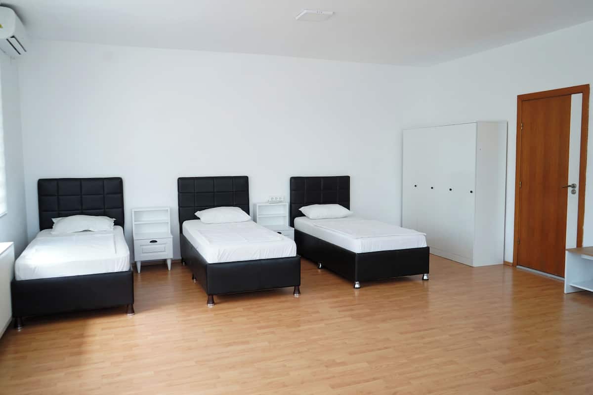 A room with three beds, a wardrobe, and a white door.