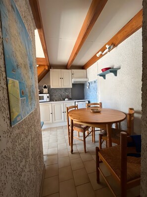 Una cucina con mobili bianchi, un tavolo da pranzo in legno e una mappa appesa al muro.
