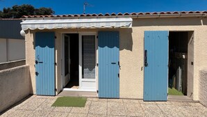 A building with a tiled roof, a small entrance with a door, and a window.