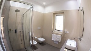Une salle de bain moderne avec une douche à parois de verre, des toilettes, un lavabo et une fenêtre.