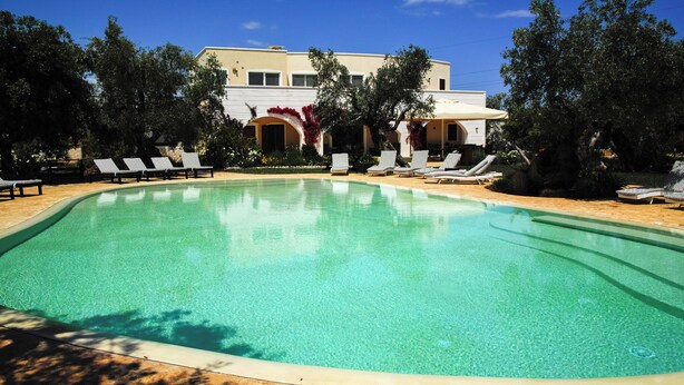 Une piscine avec des chaises longues et un bâtiment en arrière-plan.