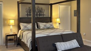 A four-poster bed with a dark wooden frame, a patterned bedspread, and two bedside lamps.