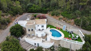 A multi-story stone building with a swimming pool, outdoor seating, and a staircase leading to the upper levels. - Villa Familia located on the Montgo with stunning views over the bay of Denia. (Dénia)