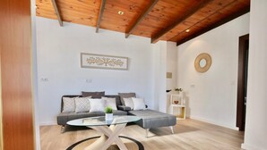 A modern living room with a grey sectional sofa, a glass coffee table, and a wooden ceiling. - Villa Familia located on the Montgo with stunning views over the bay of Denia. (Dénia)