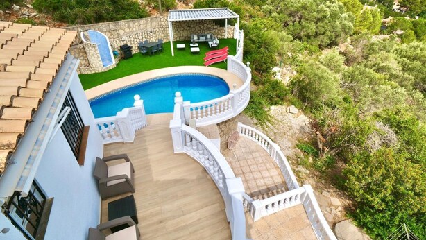 A pool area with a stone wall, a covered seating area, and a view of the surrounding landscape. - Villa Familia located on the Montgo with stunning views over the bay of Denia. (Dénia)