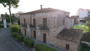 Un bâtiment en pierre de deux étages, doté de balcons, avec une enseigne indiquant qu’il s’agit d’un hôtel, et une rue pavée devant.