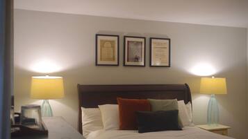 Una habitación de hotel con una cama, dos lámparas de noche y tres certificados enmarcados en la pared.