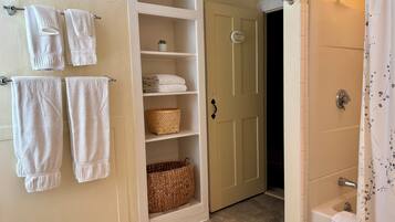 A bathroom with a shower, a towel rack with towels, a storage unit with baskets, and a door labeled "PRIVATE for Deborah".
