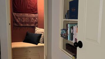 Una habitación acogedora con una cama empotrada, una estantería y una cesta de mimbre.