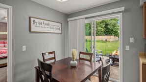 A dining area with a wooden table and chairs, a vase with dried plants, and a sign on the wall. - Near Razorback Stadium & Attractions, Firepit (Springdale)