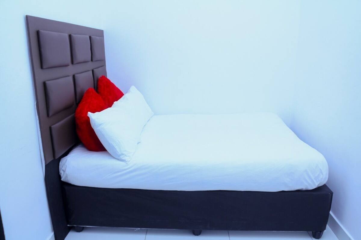 Ein Einzelbett mit dunklem Kopfteil und weißer Bettwäsche.