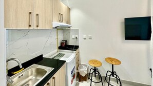 A compact kitchen with a sink, stove, and two stools. - Chic Studio apartment in fabulous Dubai with WiFi, AC (Dubai)