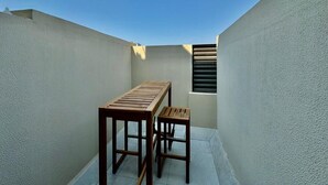 A small, enclosed outdoor space with a wooden table and bench, a window with blinds, and a clear blue sky. - Chic Studio apartment in fabulous Dubai with WiFi, AC (Dubai)