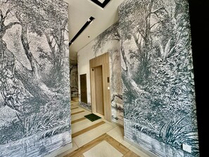 Un couloir avec un papier peint à motifs et un plancher en bois.
