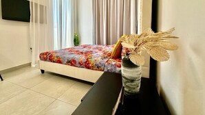 A bedroom with a bed, a desk, a vase with dried plants, and a television on the wall. - Chic Studio apartment in fabulous Dubai with WiFi, AC (Dubai)