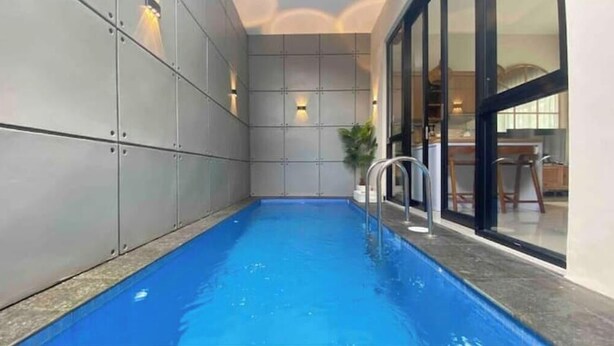 Uma piscina interior com parede revestida em azulejos e guarda-corpo de metal.