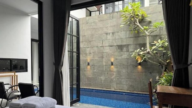 Ett hotellrum med en säng, ett skrivbord, en stol, en tv och utsikt över en swimmingpool.