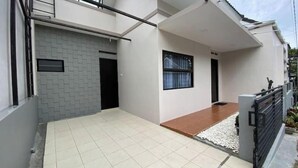 A modern house with a tiled patio, a small entryway, and a visible door. - The Pines Smart Homes (Batu)