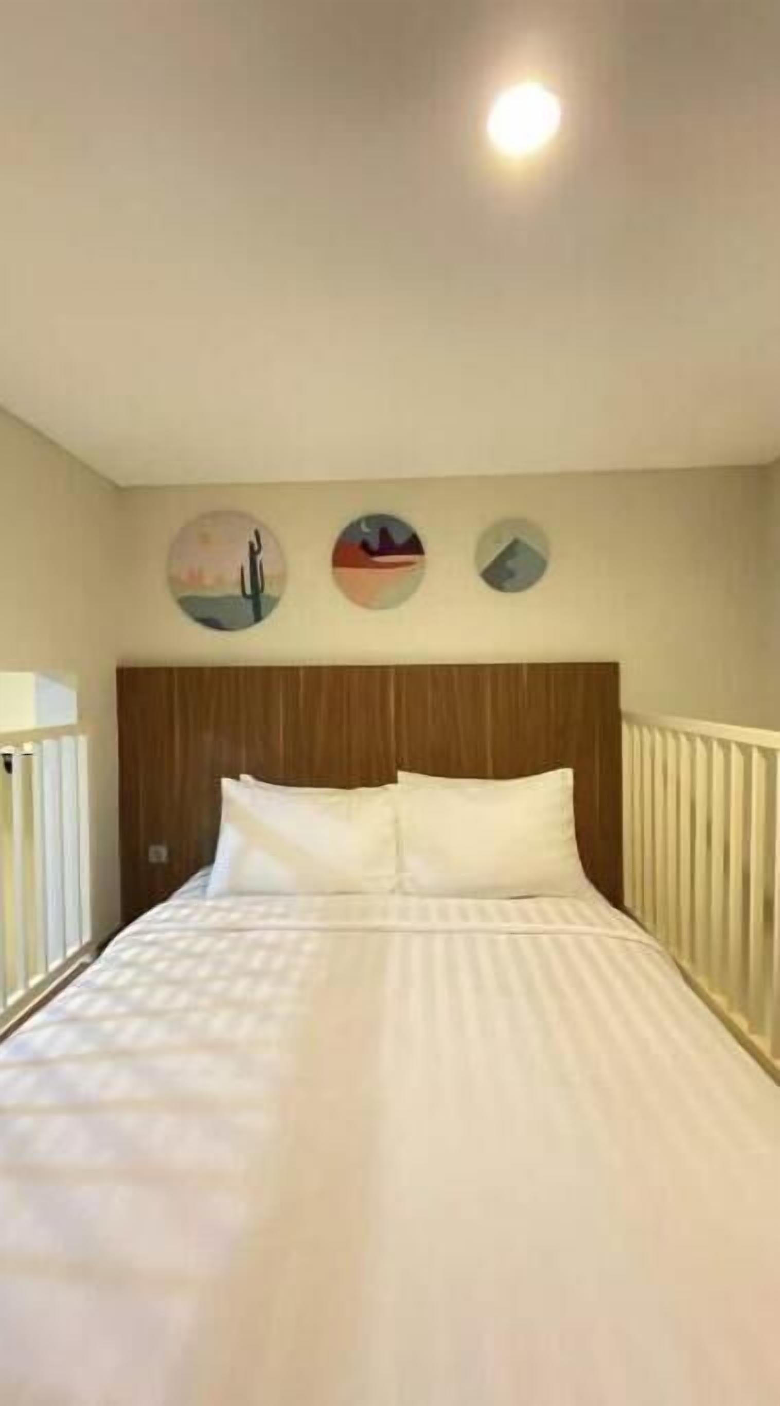 Een net opgemaakt bed met witte lakens in een kamer met een houten hoofdeinde en een witte leuning aan de zijkant.