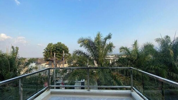 A balcony with a metal railing overlooking a residential area with palm trees and houses. - Aira Villas Private Pool (Junrejo)