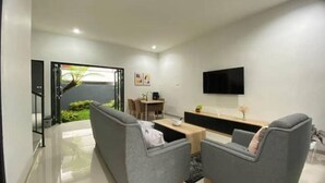 Een moderne woonkamer met een bank, een salontafel en een flatscreen televisie aan de muur.