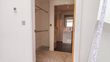 A hallway with a door leading to a bathroom and a kitchen area.