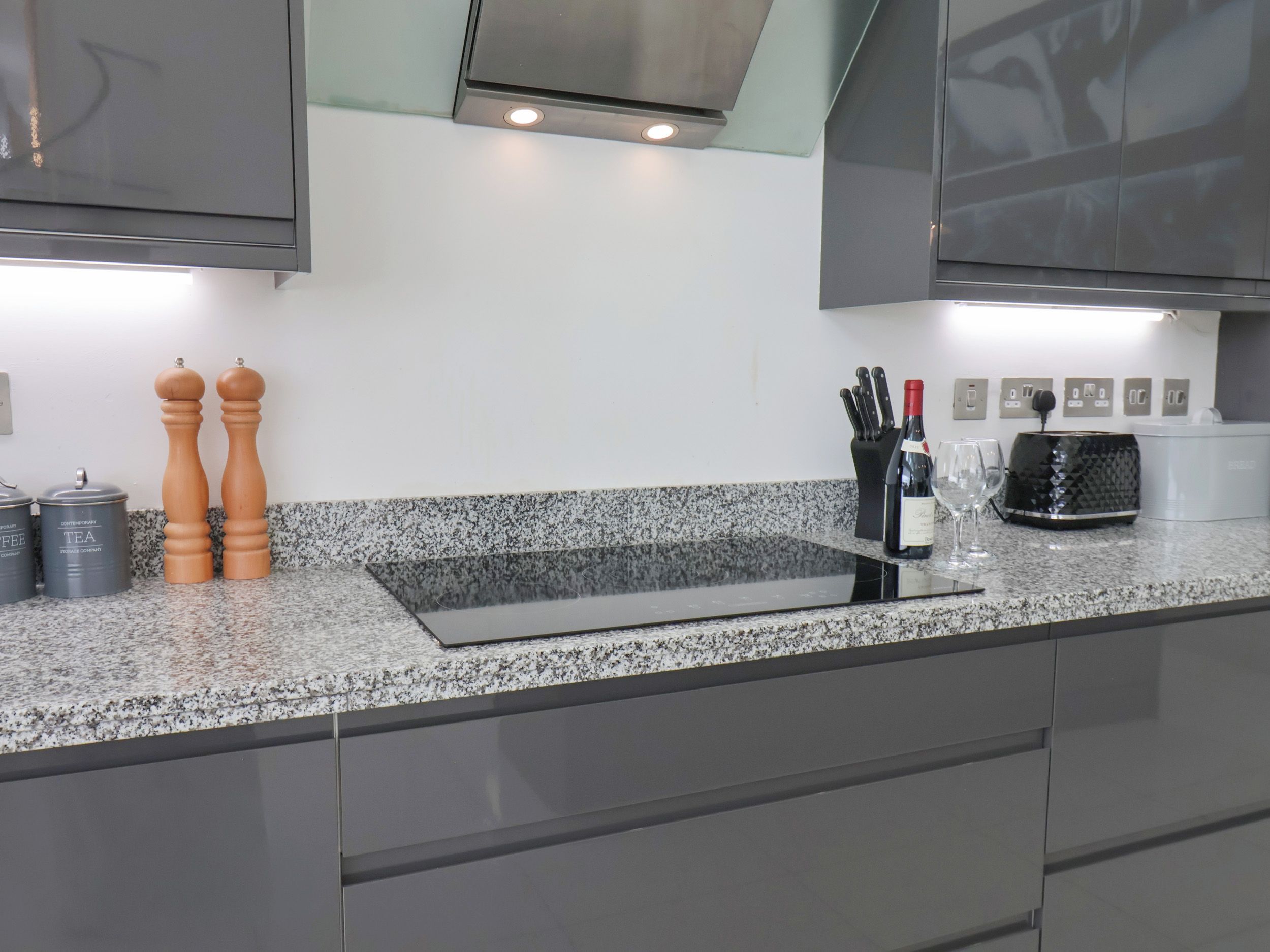 Cozinha moderna com bancadas de granito, eletrodomésticos de aço inoxidável e forno embutido.