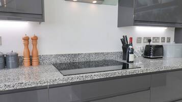 Cozinha moderna com bancadas de granito, eletrodomésticos de aço inoxidável e forno embutido.