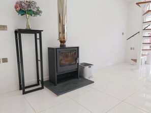A modern living room with a fireplace, a black metal frame, and a vase of flowers on a table. - Meadow View (Beverley)