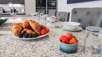 Ein Frühstückstisch mit Croissants, Brombeeren und Erdbeeren auf einer Marmorplatte.