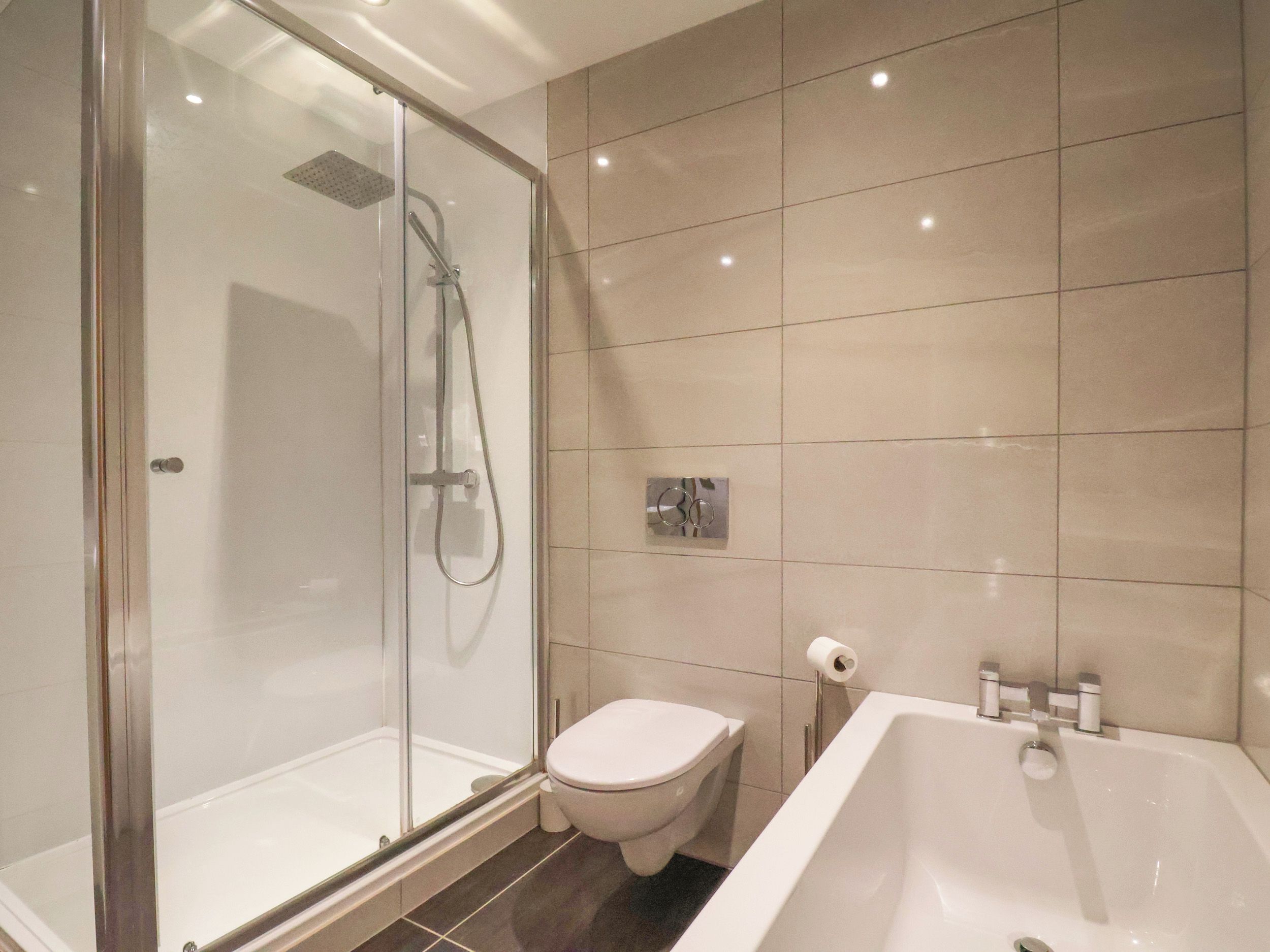 A modern bathroom with a glass-enclosed shower, a toilet, and a bathtub.
