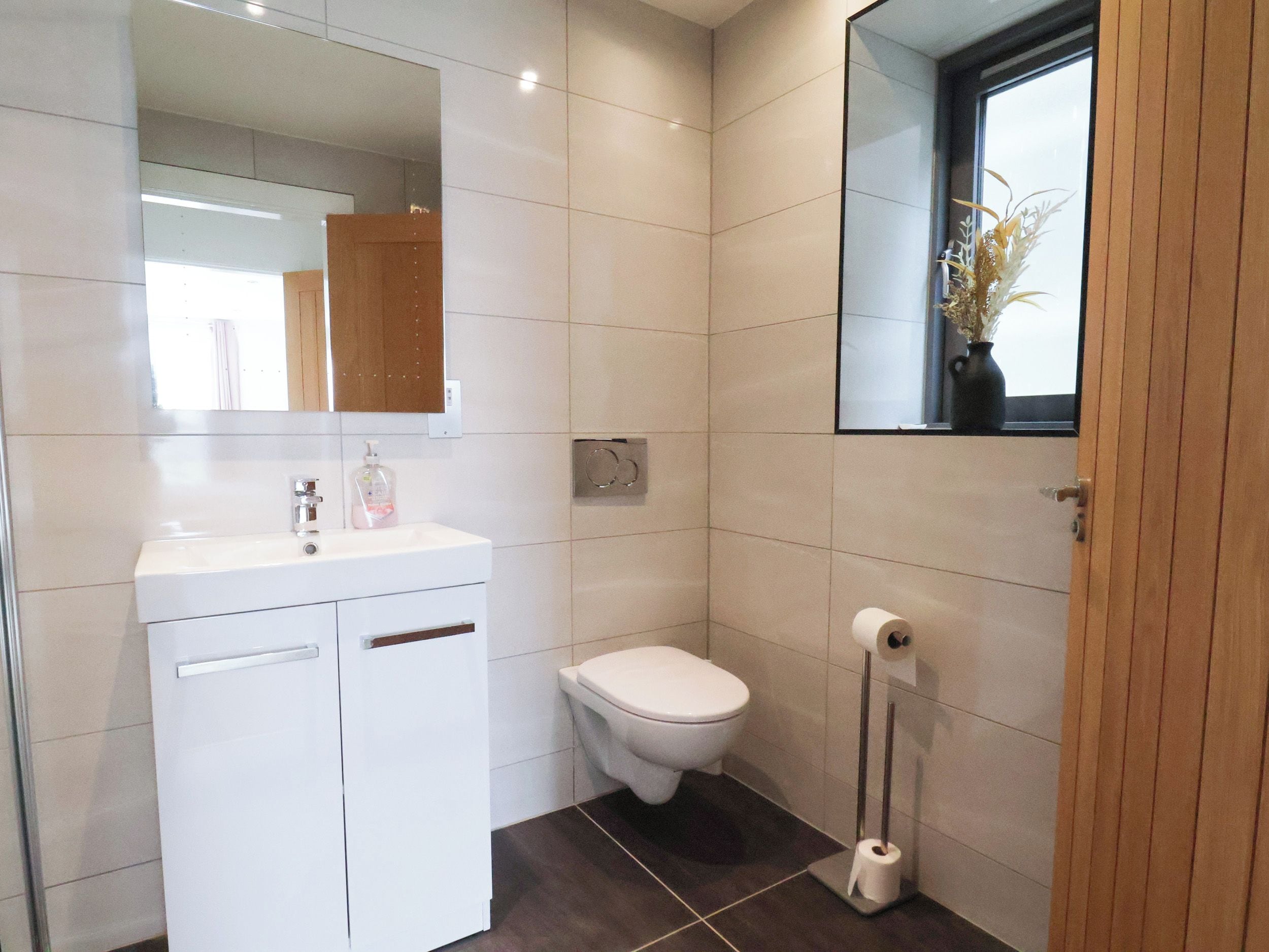Un baño moderno con un lavabo blanco, un inodoro y un espejo.