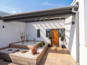 A modern house with a wooden door, a small window, and a covered patio area. - Meadow View (Beverley)