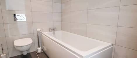 Un baño con inodoro, bidé y bañera.