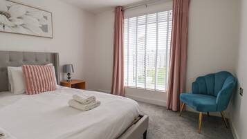 Ein Hotelzimmer mit einem Bett, einem Nachttisch, einem Stuhl und einem Fenster mit Vorhängen.